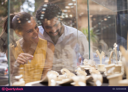 Middle Eastern couple happily choosing a wedding ring together at a jewelry store with family photo 3204408