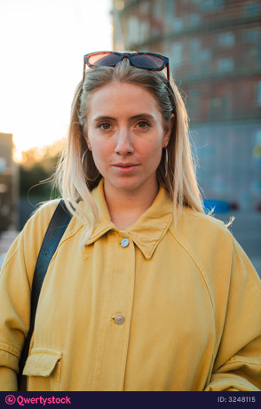 Confident young woman standing with a focused expression showcasing her personal style in sunlight photo 3248115