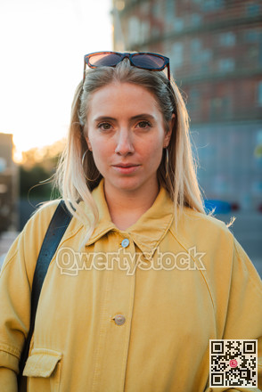 Confident young woman standing with a focused expression showcasing her personal style in sunlight photo 3248115
